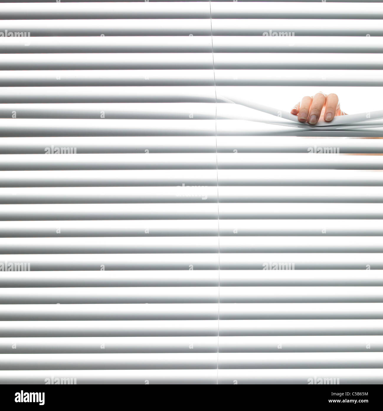 Person looking through blinds Stock Photo