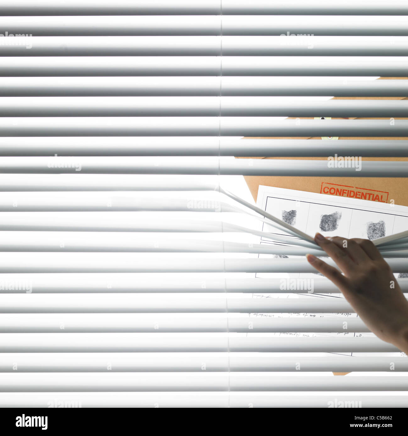 Person looking through blinds Stock Photo