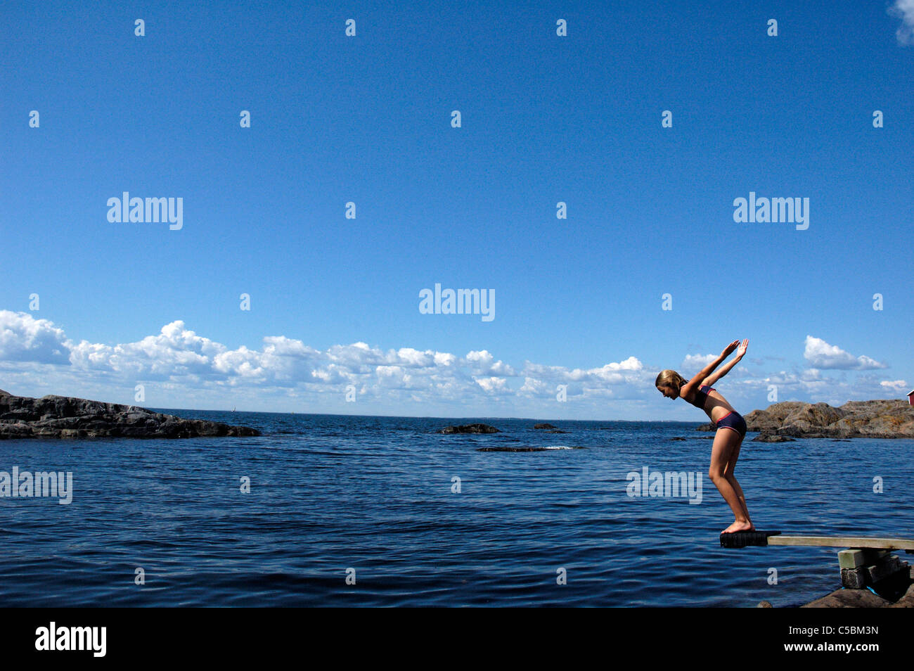 Side View Of A Girl About To Jump Into The Sea From Diving Board Side View Of A Girl About To Jump Into The Sea From Diving Board