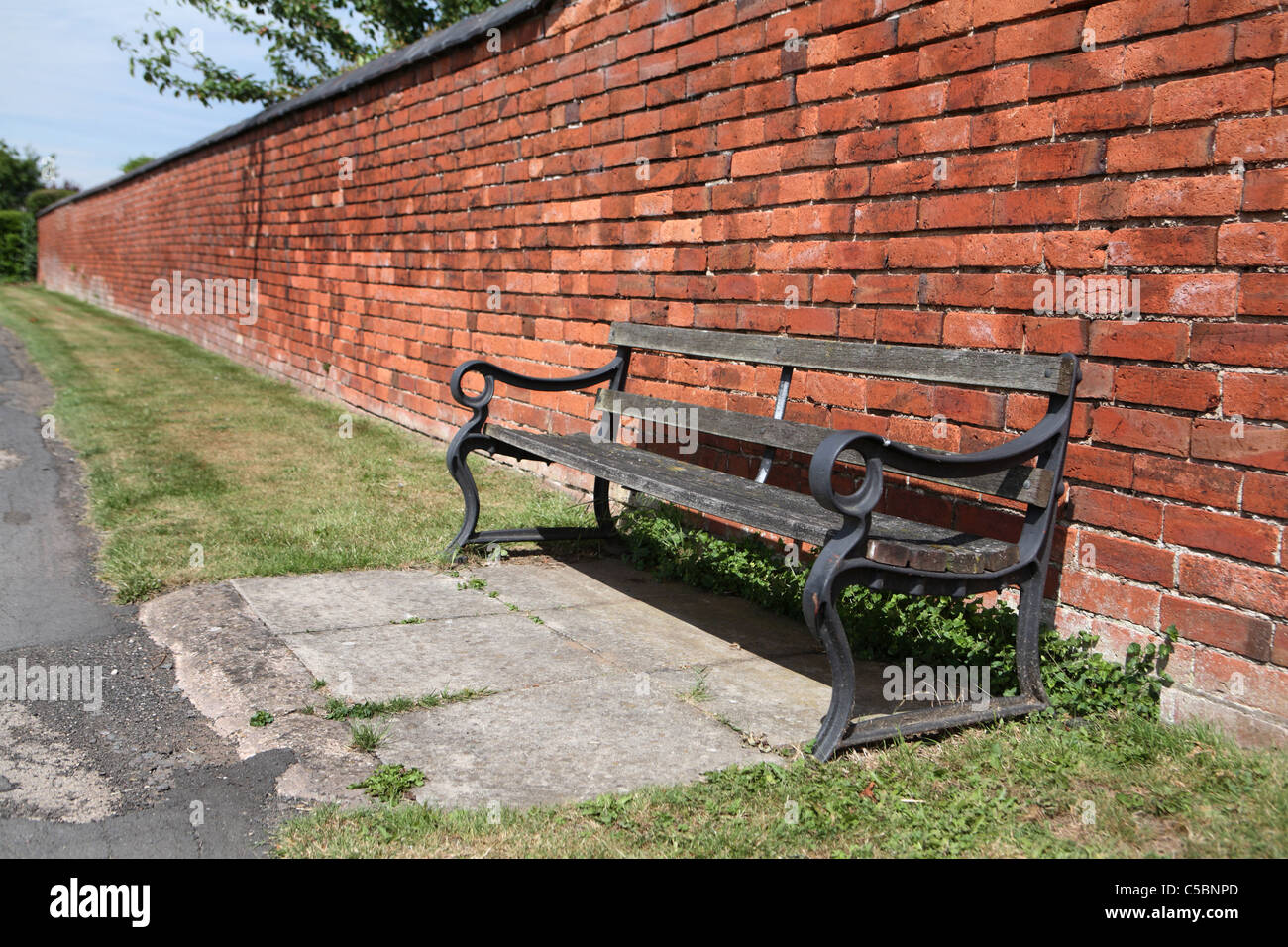 wooden bench next to Victorian brick wall Stock Photo