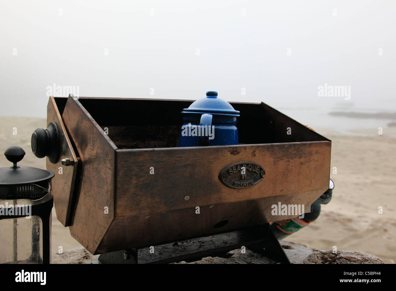 making hot water for coffee and tea camping on a sandy beach on a foggy