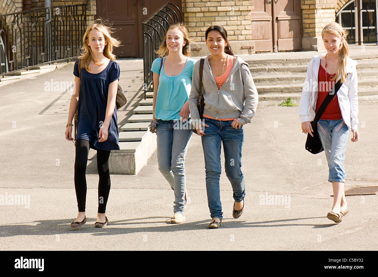 Four happy school girls walking together in the schoolyard Stock Photo -  Alamy