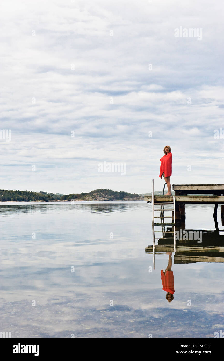 Woman below cloudy sky on the bridge reflected in the peaceful water Stock Photo