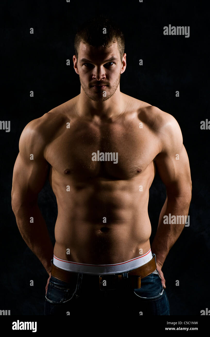 Portrait of a young muscular shirtless man against black background Stock Photo