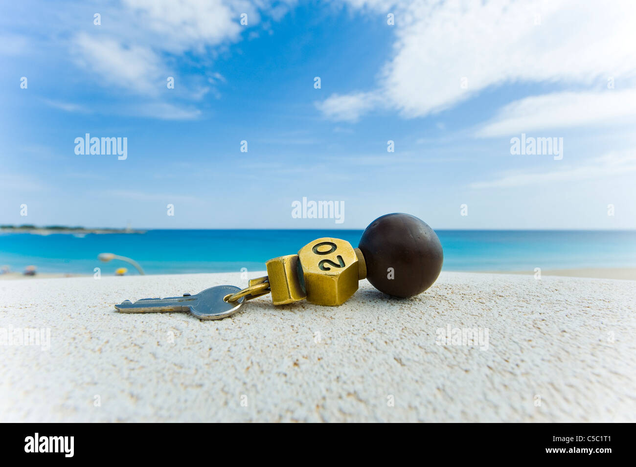 Close-up of hotel key on the sand with blue sea in the background at a beach Stock Photo