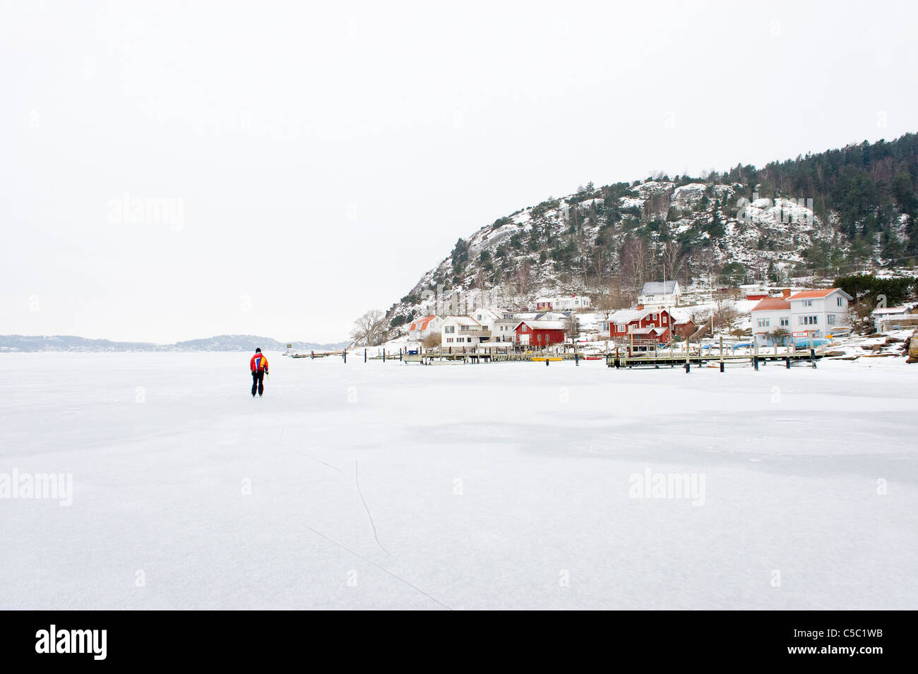 Mid distance of a lone skater on frozen lake by townscape Stock Photo