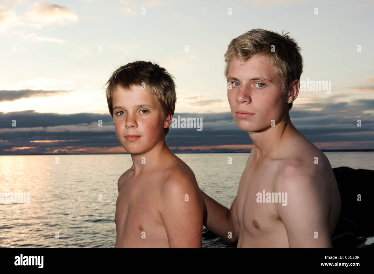 Portrait of two shirtless boys against the sea on a beach Stock Photo