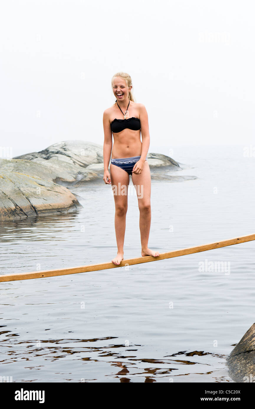 Full length of a teenage girl in bikini smiling on a plank over the water Stock Photo