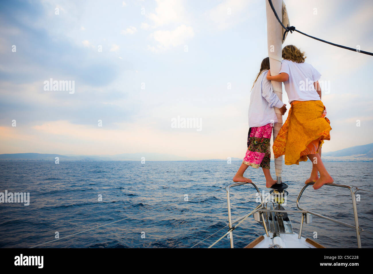 Rear view of two girls on pulpit in sailboat looking at the sea Stock Photo