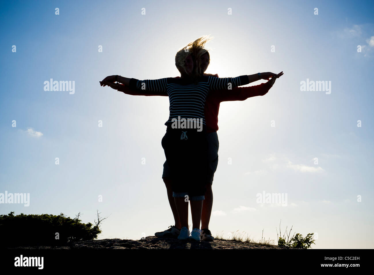 Silhouette couple with arms outstretched in backlight against clear sky Stock Photo
