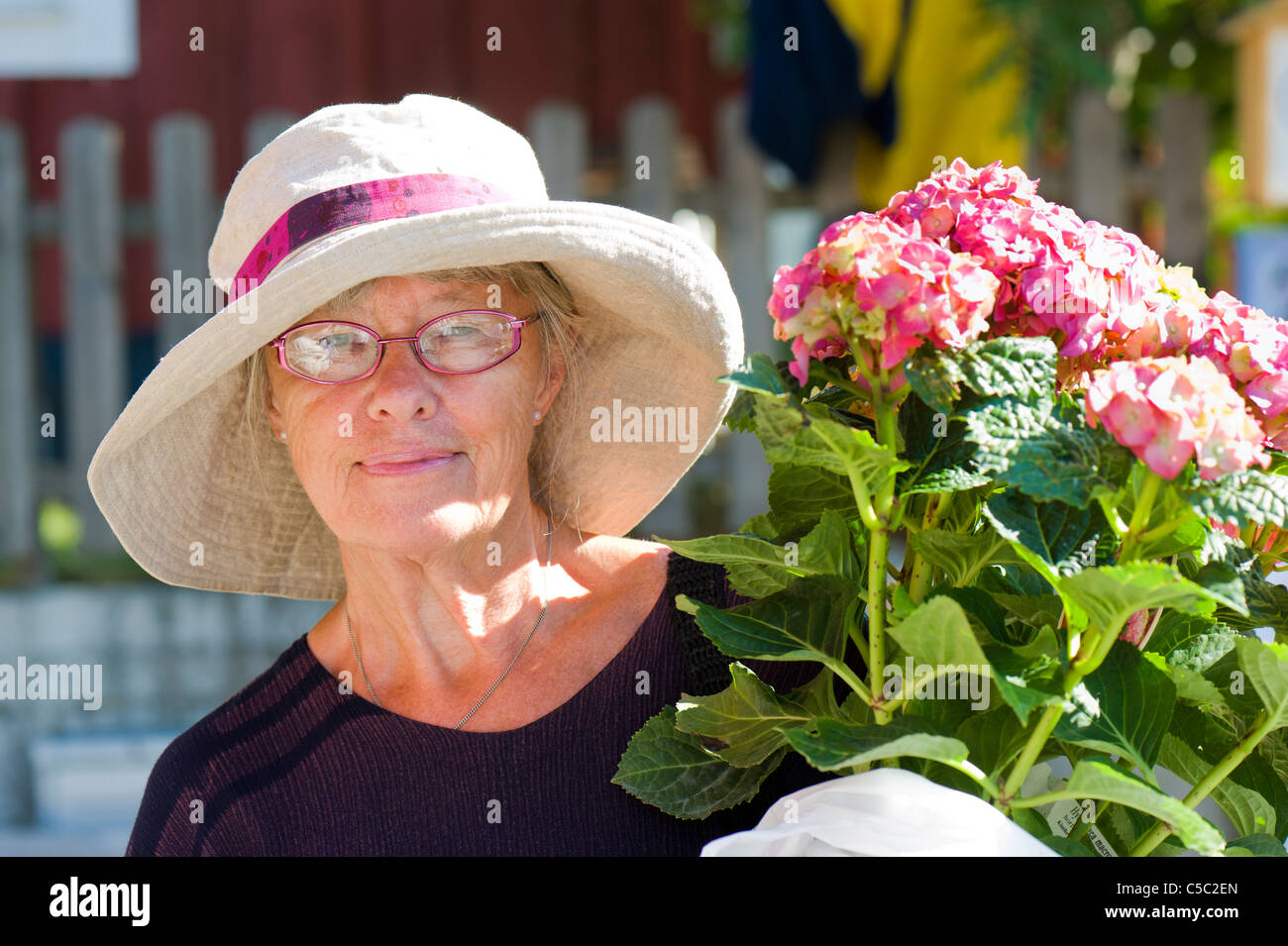 Close-up portrait of a senior woman with hat and hydrangea flowers Stock Photo