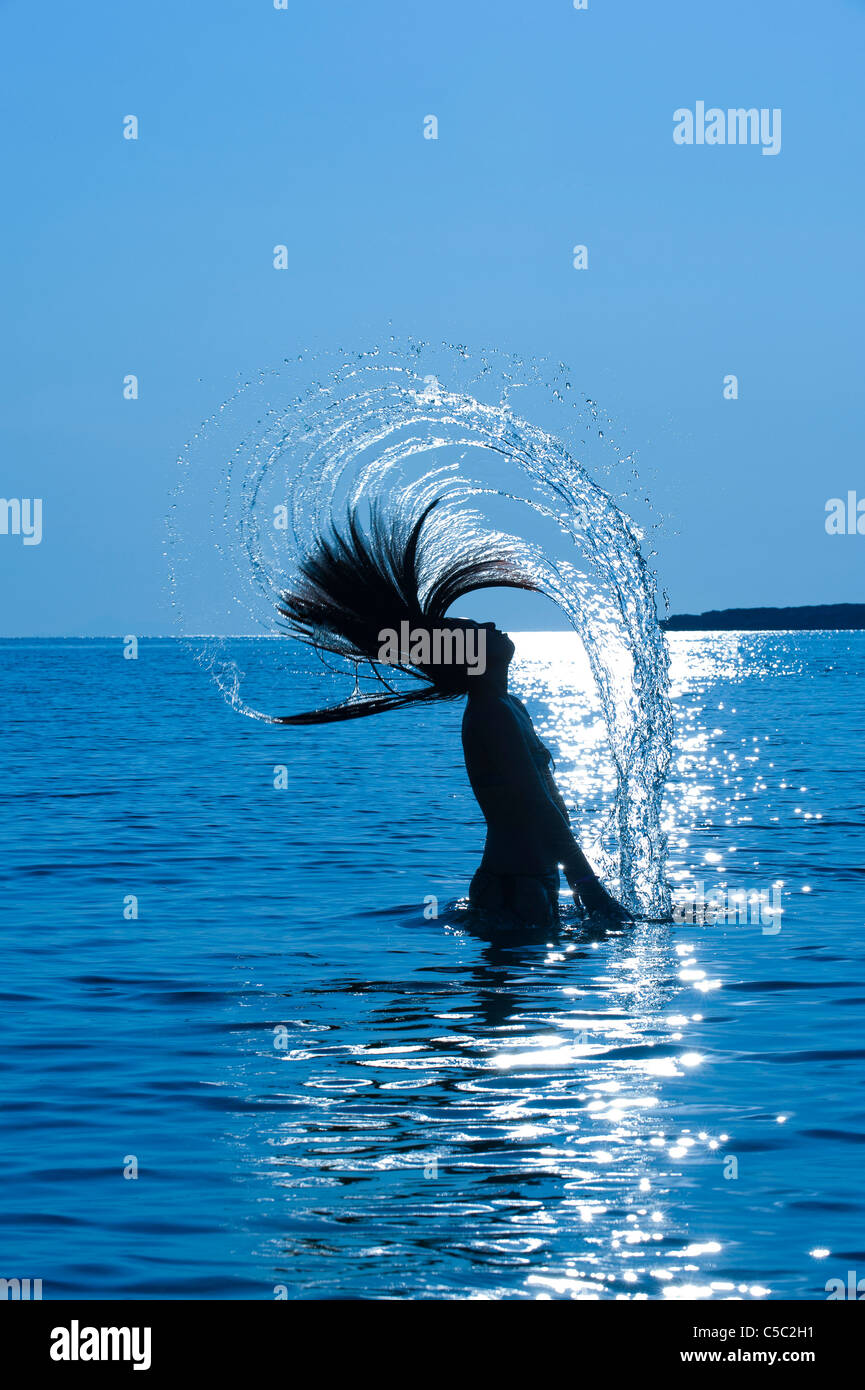 Silhouette of a young long haired woman in the back light hires stock