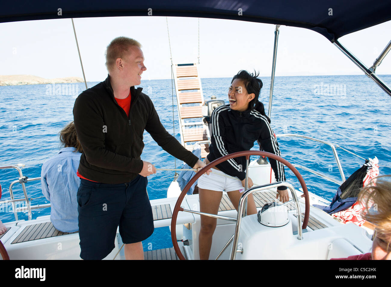 Happy teenage boy and girl steering a sail boat in the sea Stock Photo