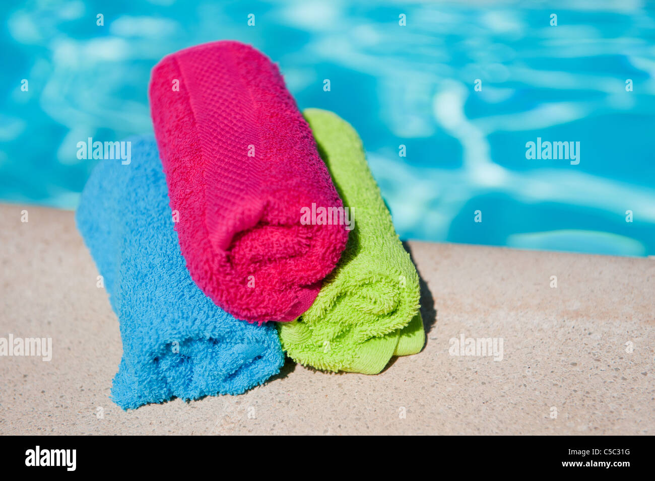 Rolled towels in various colors near the swimming pool Stock Photo