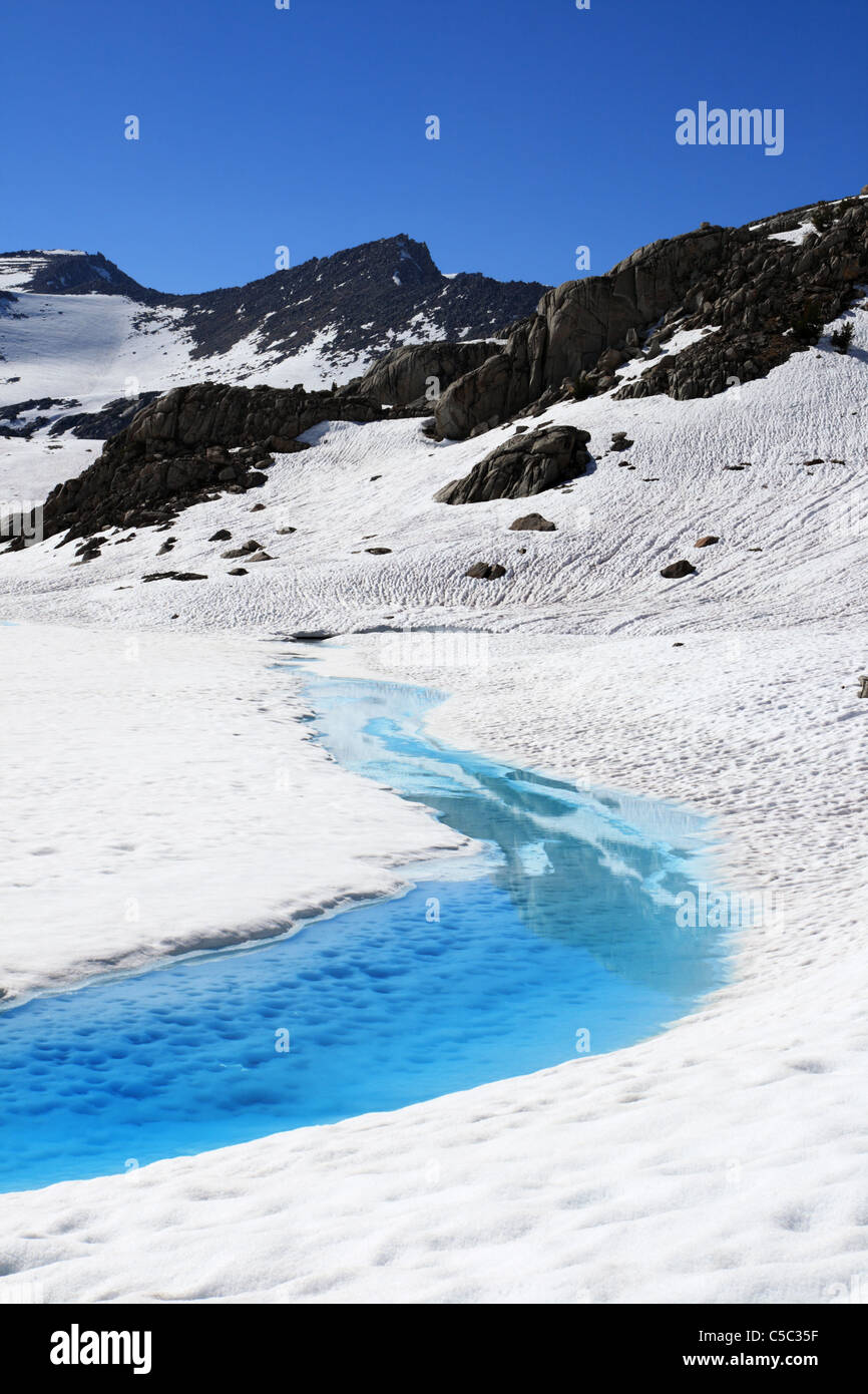 blue melting edge of a Dusy Basin lake margin melting out from the snow Stock Photo