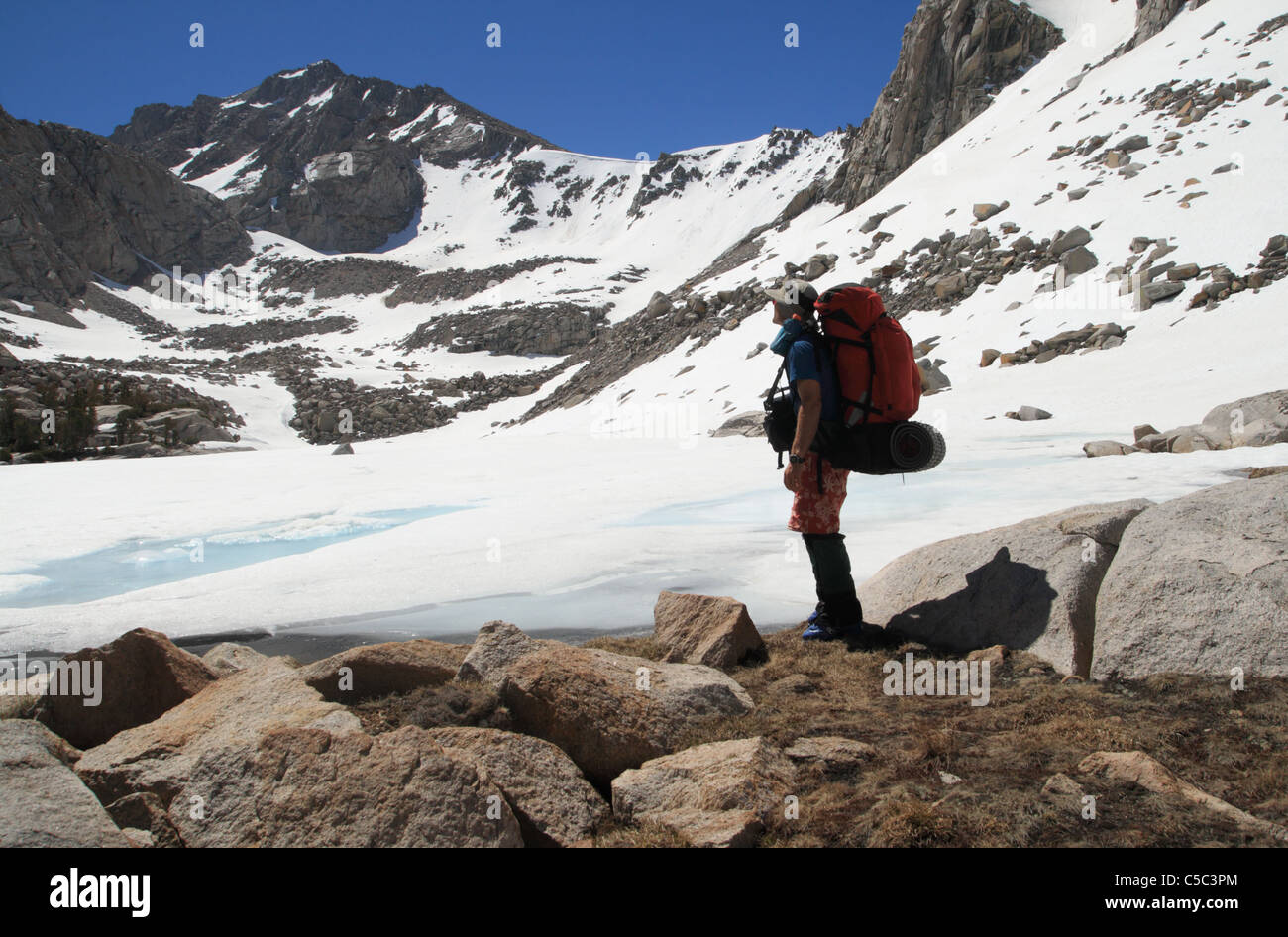 backpacker by frozen Kearsarge Lake in the Sierra Nevada Mountains with