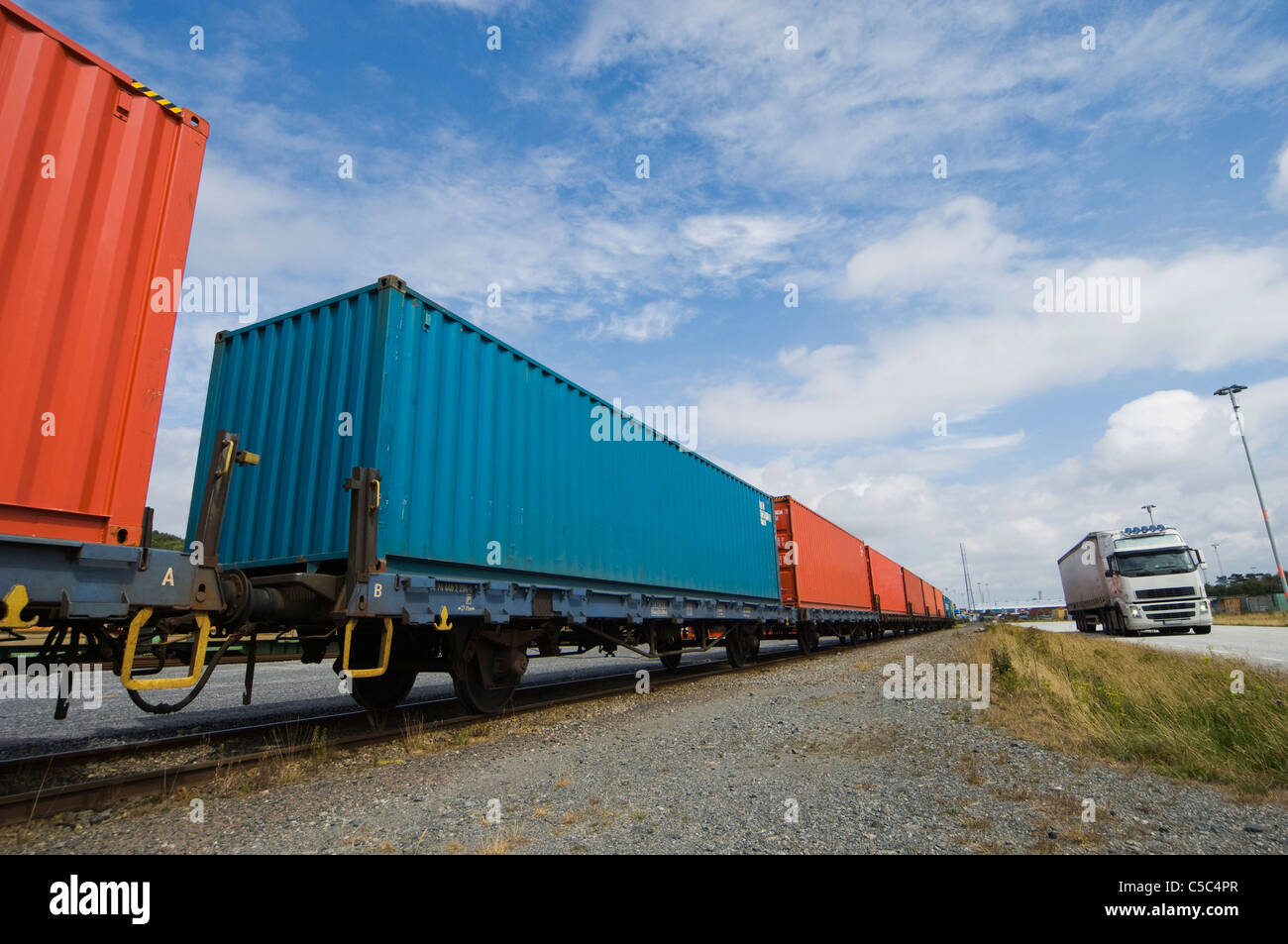 Freight rail transport by the road below cloudy sky Stock Photo