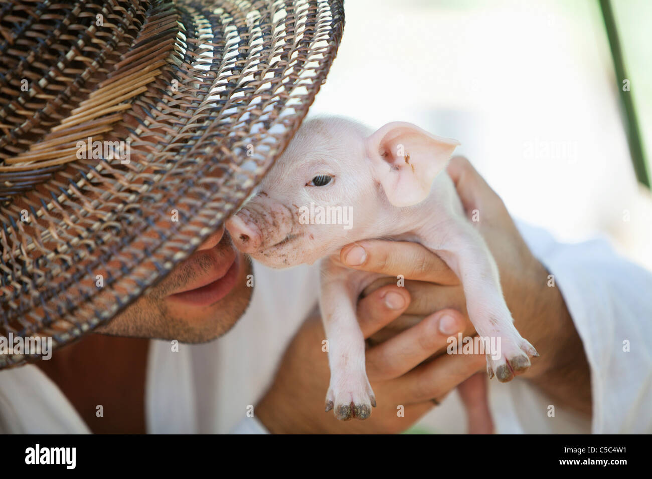 Man Holding Up A Baby Pig; Siquijor, Philippines Stock Photo