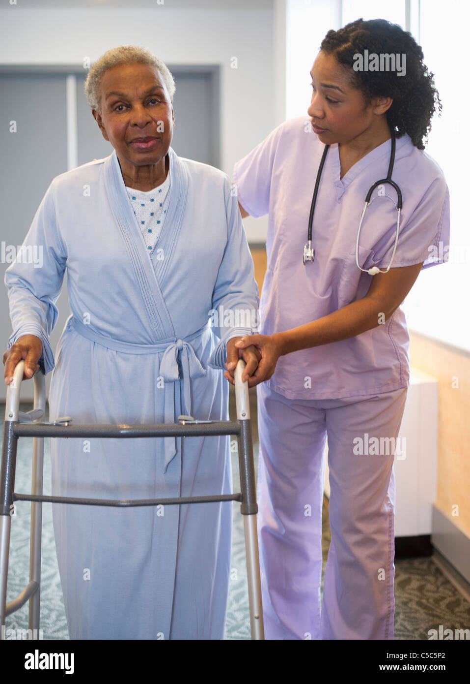 Nurse helping woman use walker in hospital hallway Stock Photo Alamy