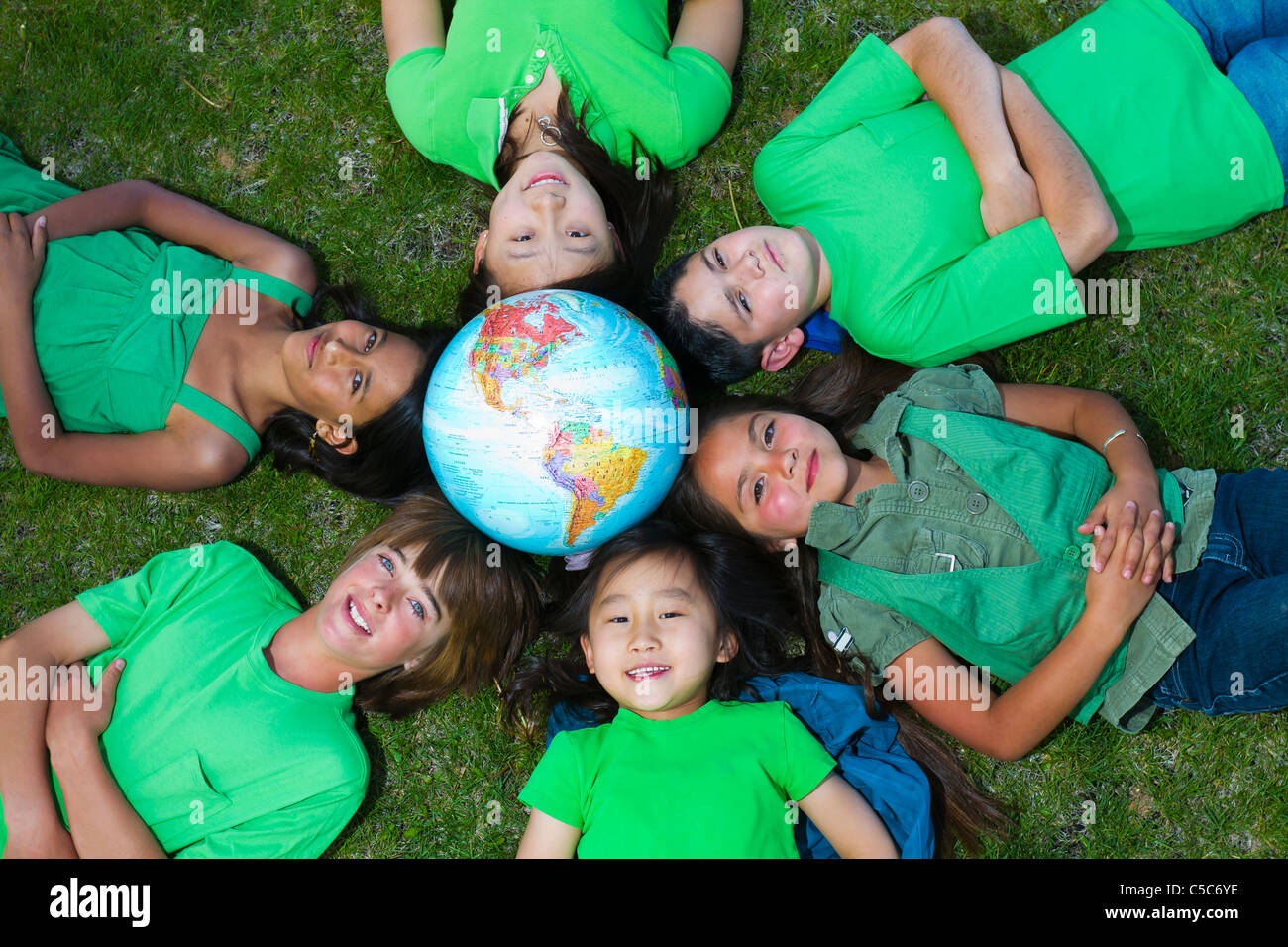 Children laying in grass around globe Stock Photo