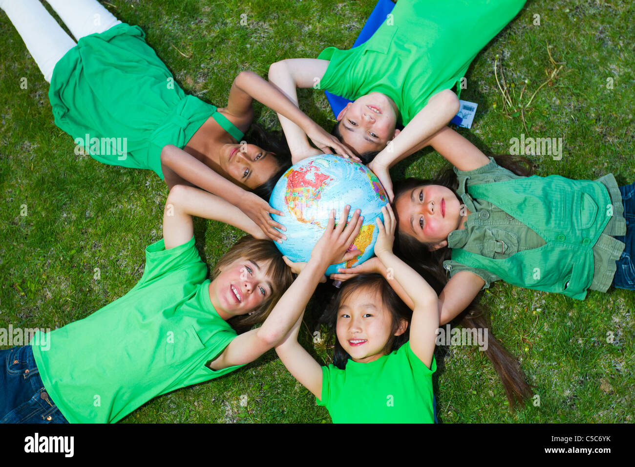 Children laying in grass around globe Stock Photo