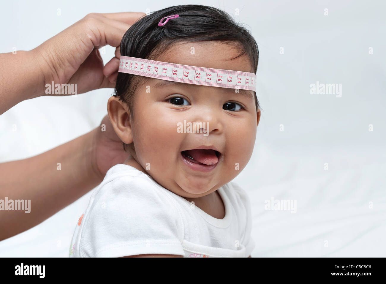 Cute baby with tape measure on head, pediatric exam measuring growth Stock Photo