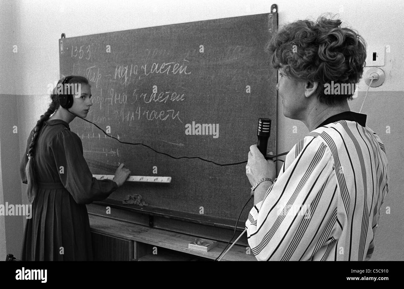 A female teacher using headphones and a microphone to aid teaching ...