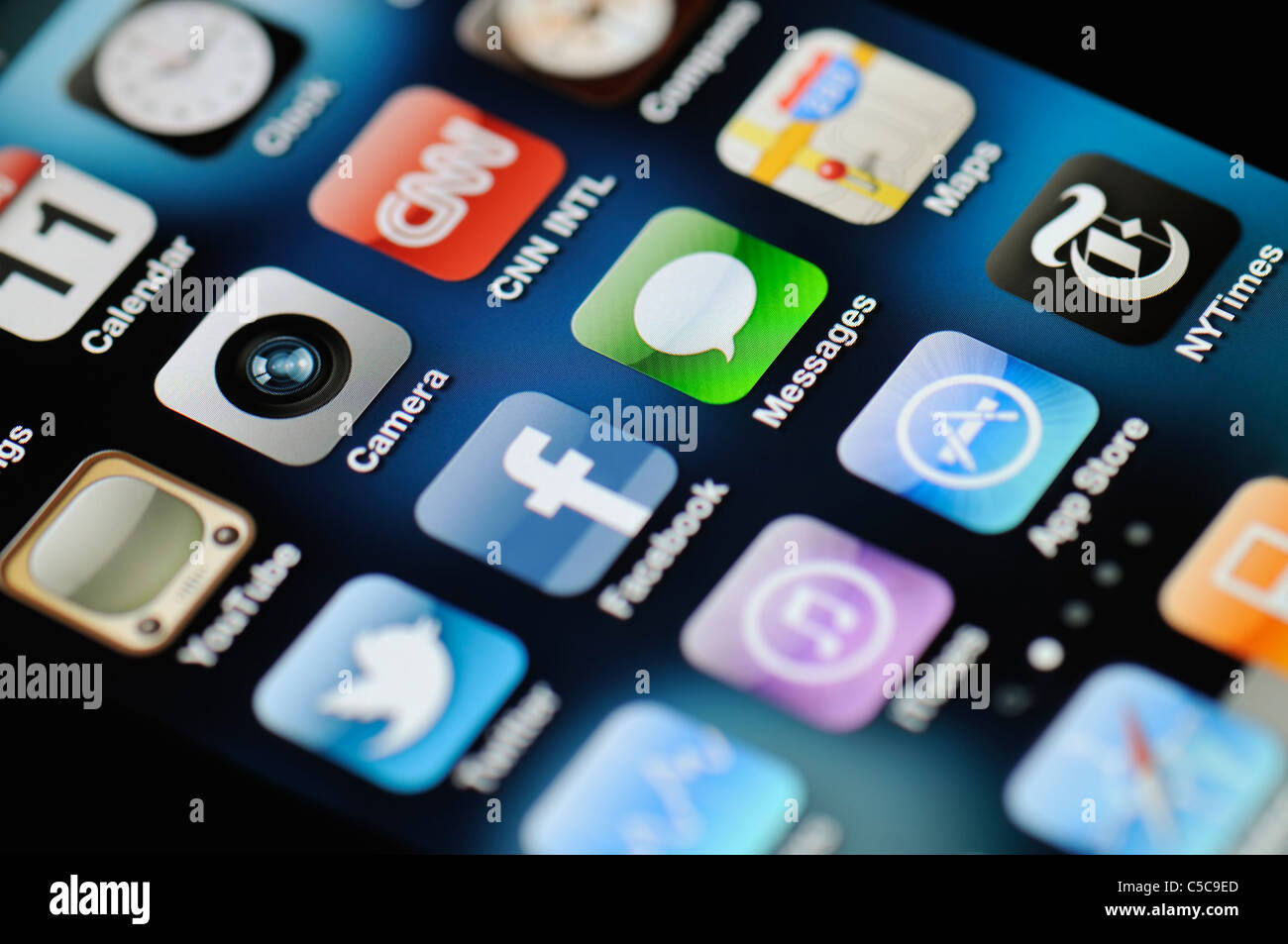 A close up of an illuminated Apple iPhone 4 screen showing the App Store and various apps Stock Photo