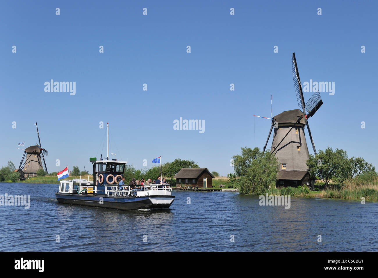 Tourists on sightseeing boat and thatched polder windmills at Kinderdijk, South Holland, the Netherlands Stock Photo