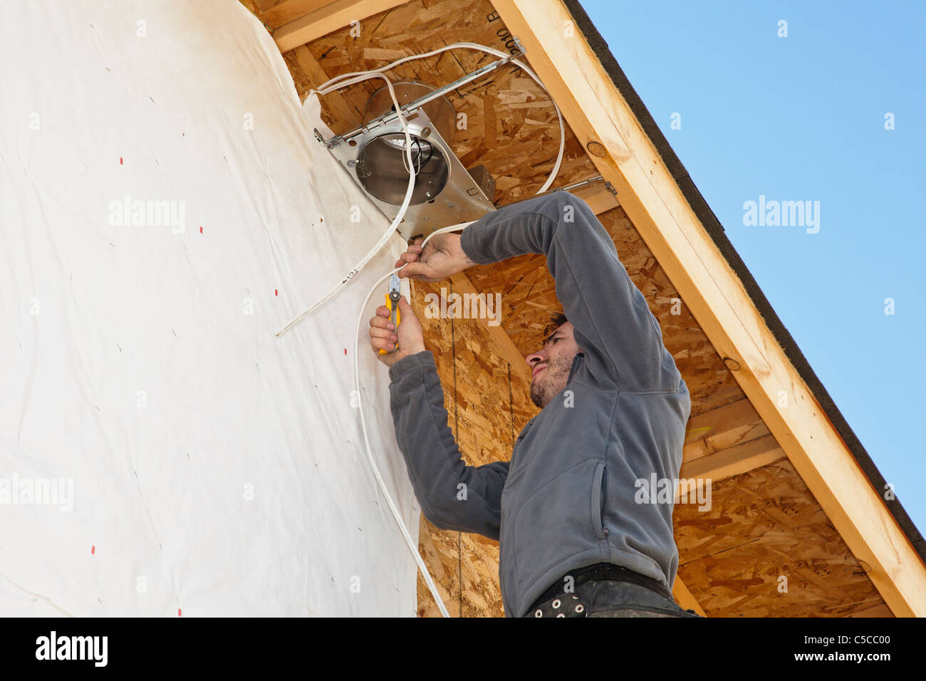 Electrician Installing Light Fixtures On House Stock Photo