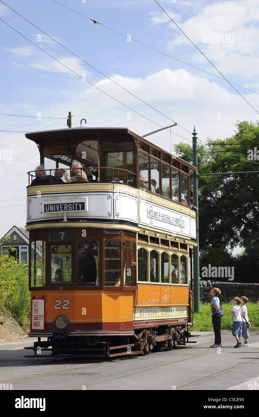 An ex-Glasgow corporation tram restored and running at the Crich Tramway Museum with children talking to the conductor Stock Photo