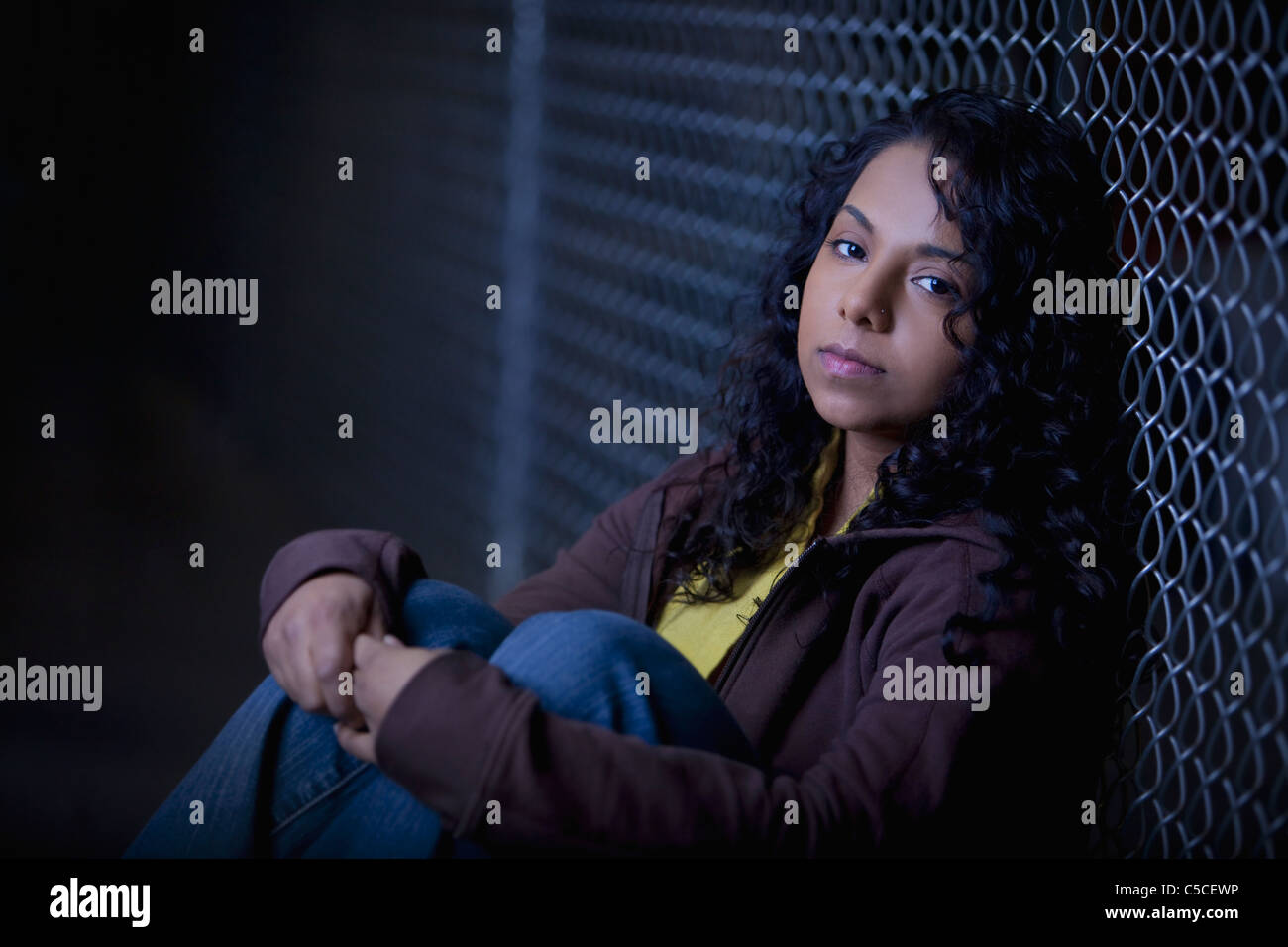 A Girl Sits Alone In The Dark Along A Chain Link Fence; Edmonton