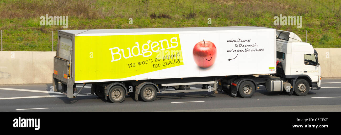 Side view of hgv supermarket food supply chain store delivery lorry truck with Budgens trailer business advertising British potatoes on UK motorway Stock Photo