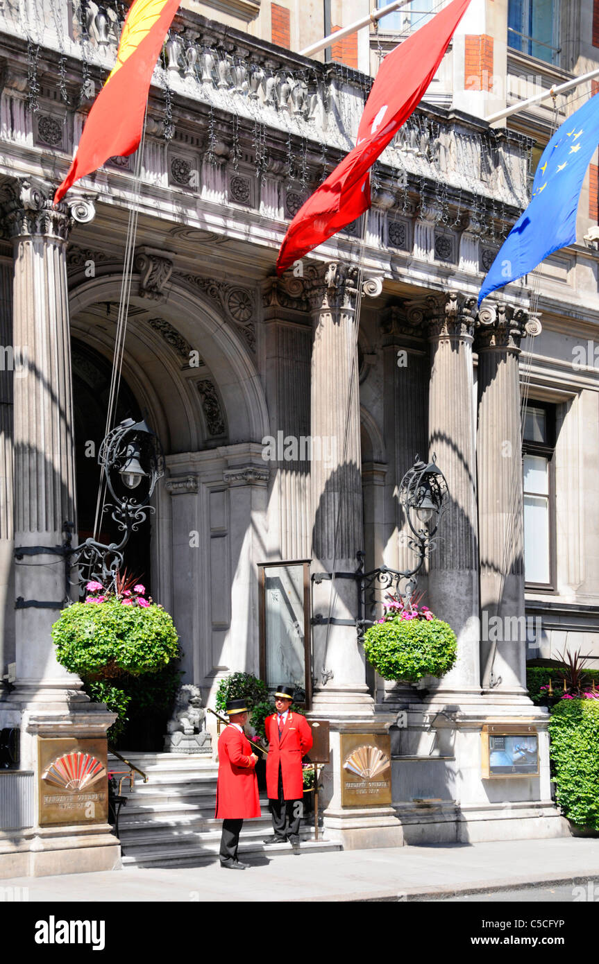 Flags above two doorman in uniform at the entrance facade to the luxury five star Mandarin Oriental Hyde Park Hotel in London Knightsbridge England UK Stock Photo