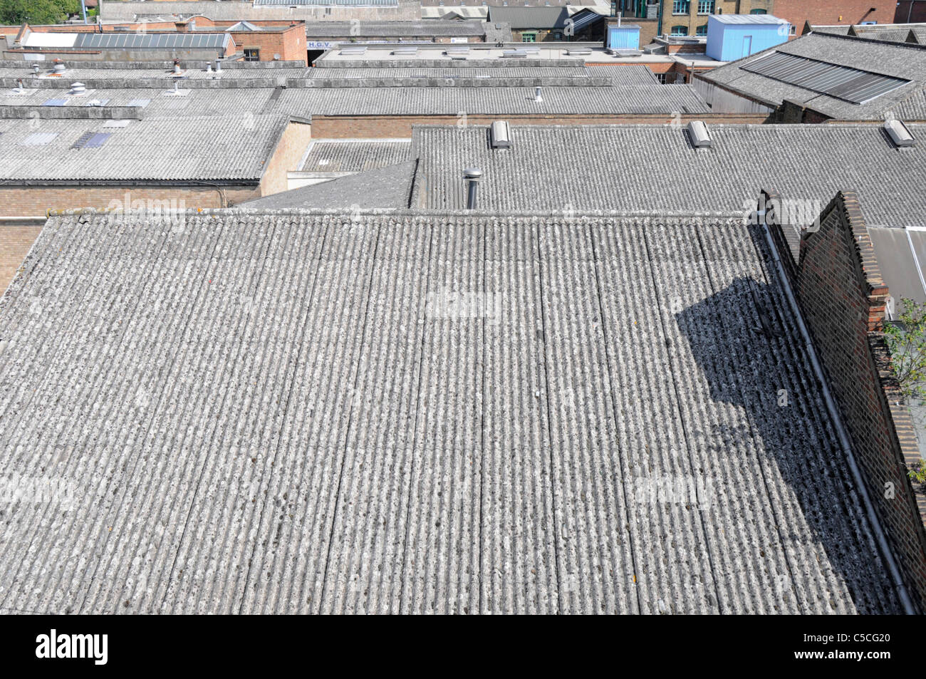 Looking down from above on urban landscape sloping grey corrugated asbestos cement roofing on industrial business units Hackney East London England UK Stock Photo