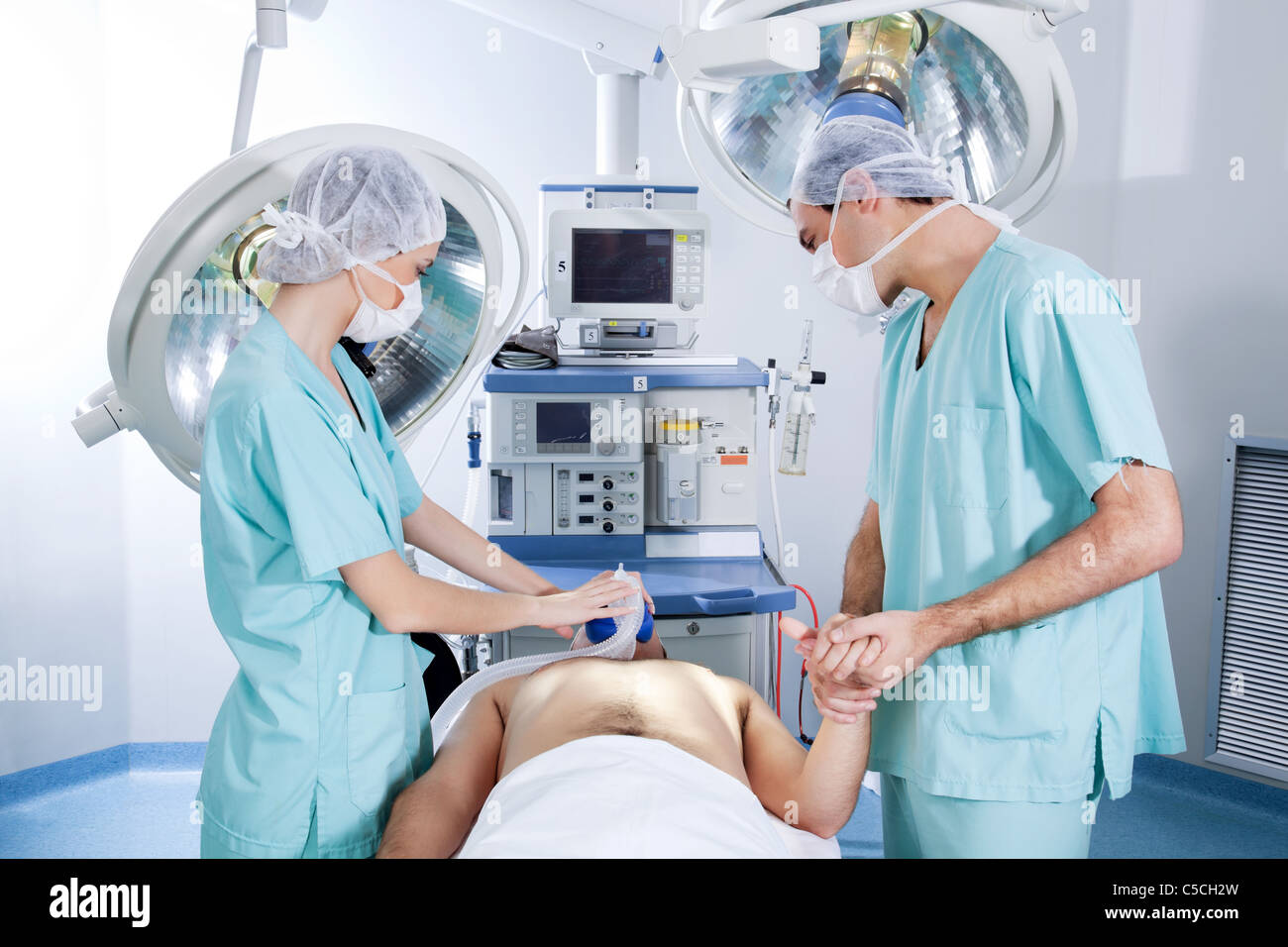 Surgeons operating on patient in an operating theatre Stock Photo