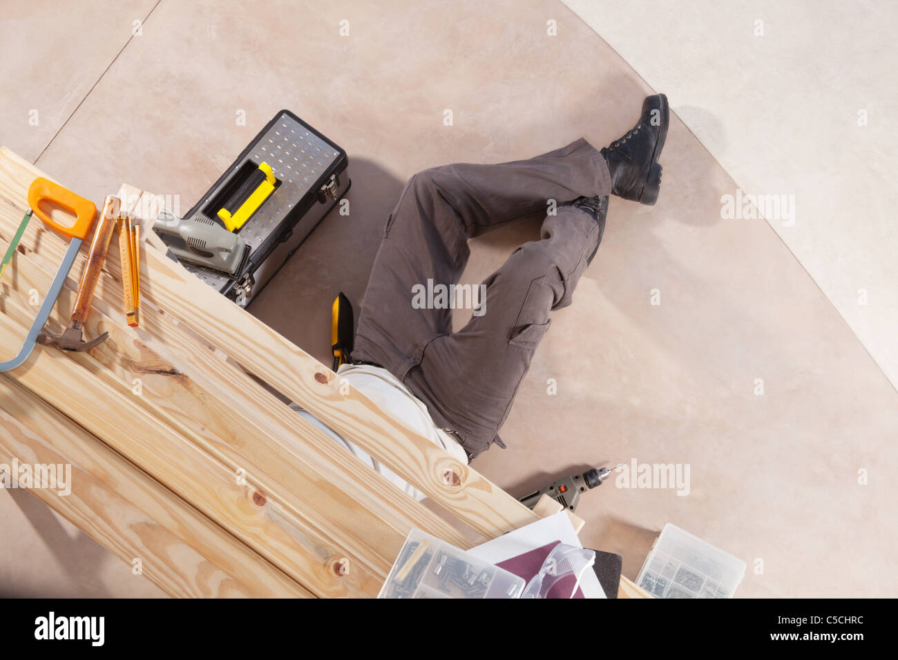 Carpenter working under the table with carpentry tools around Stock
