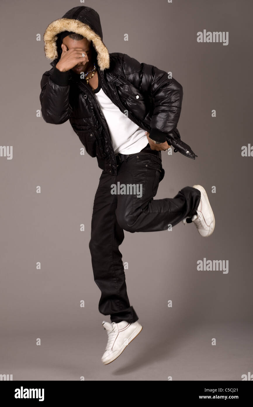 Black acrobat man dancing in studio on grey background Stock Photo