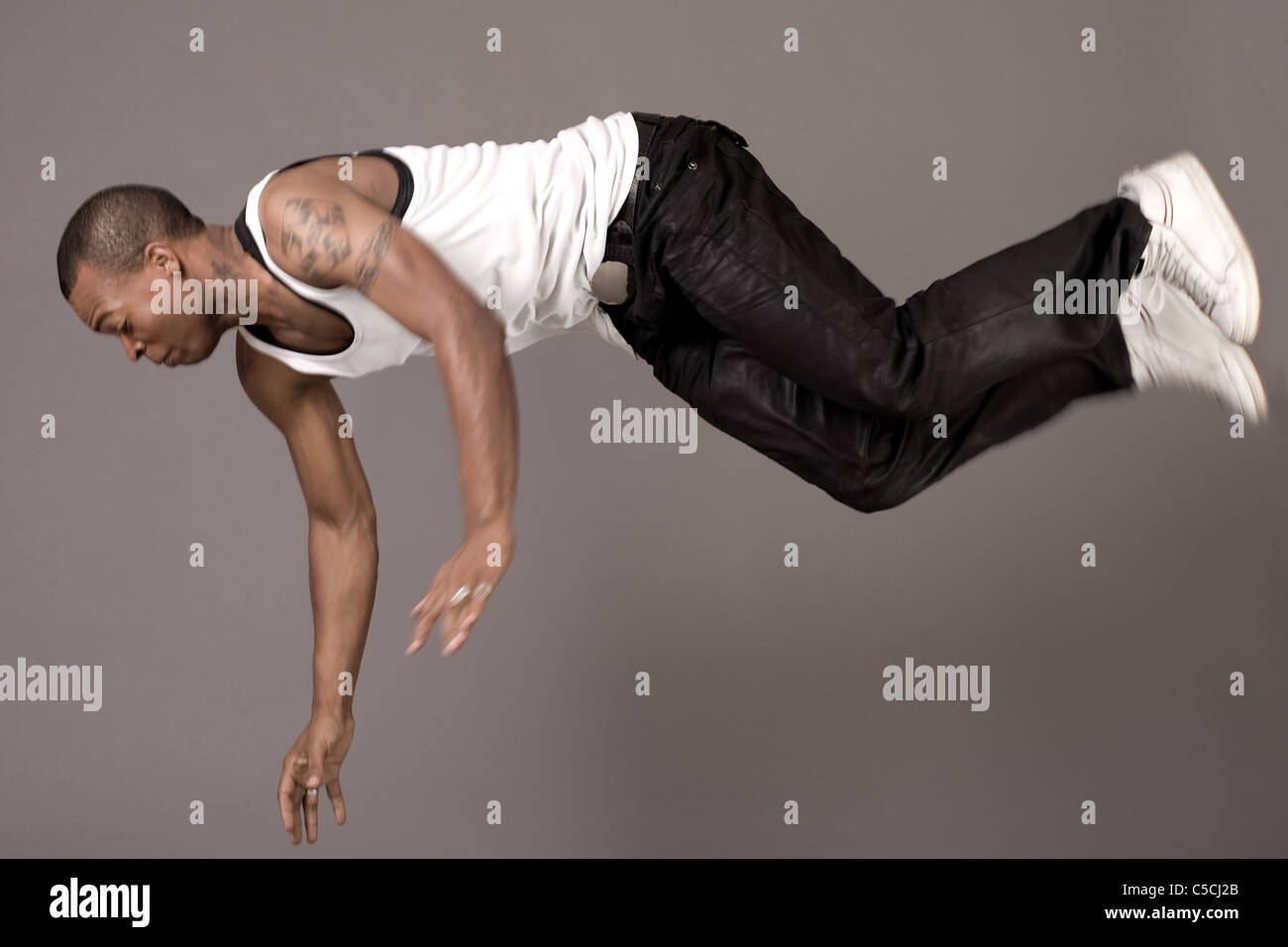 Dancer jumping to the floor on grey background Stock Photo