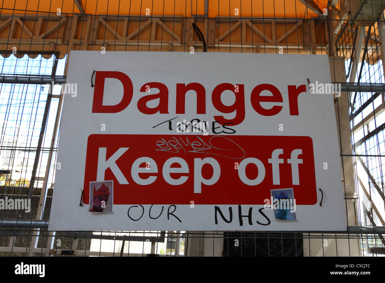Tories, Keep Off Our NHS. Protest graffiti added to Danger sign on building site, London, England Stock Photo