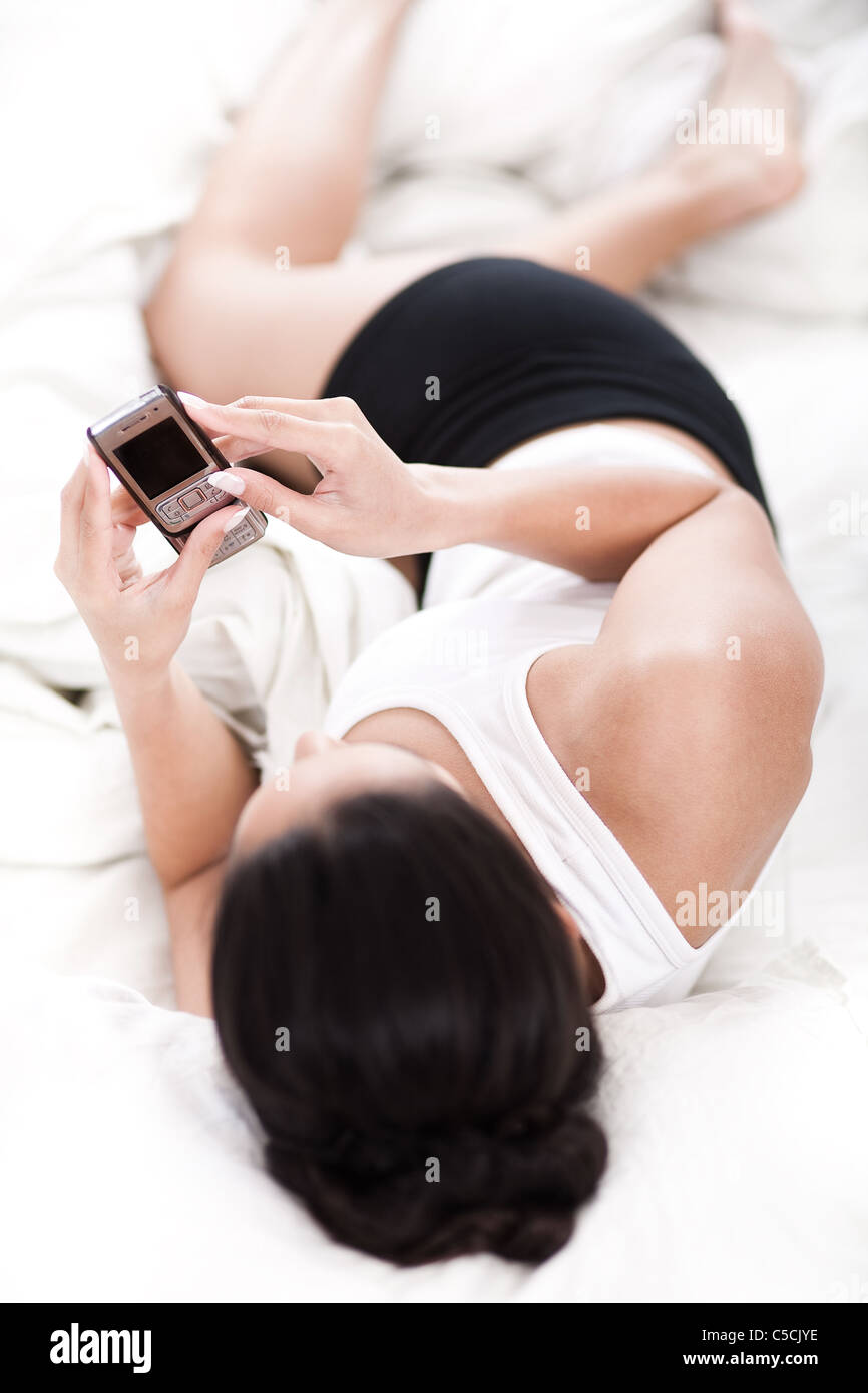 sexy woman in bed with mobile phone in white background Stock Photo