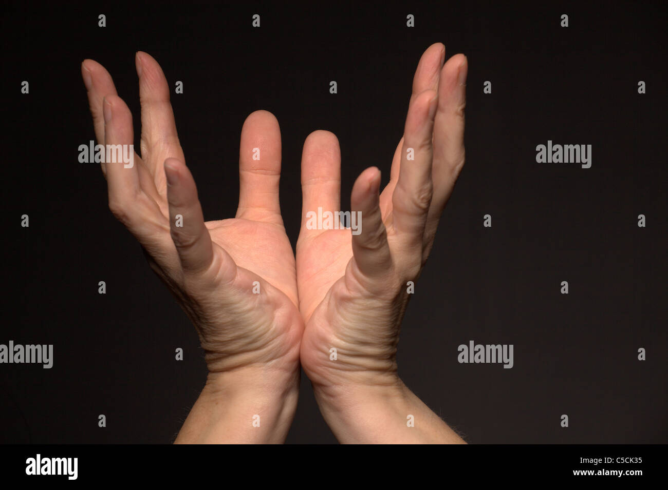 Open Hands reaching skywards Stock Photo