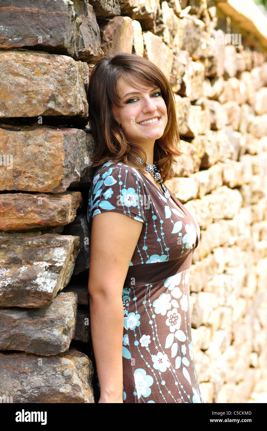 A pretty Hispanic girl leans against a stone wall Stock Photo