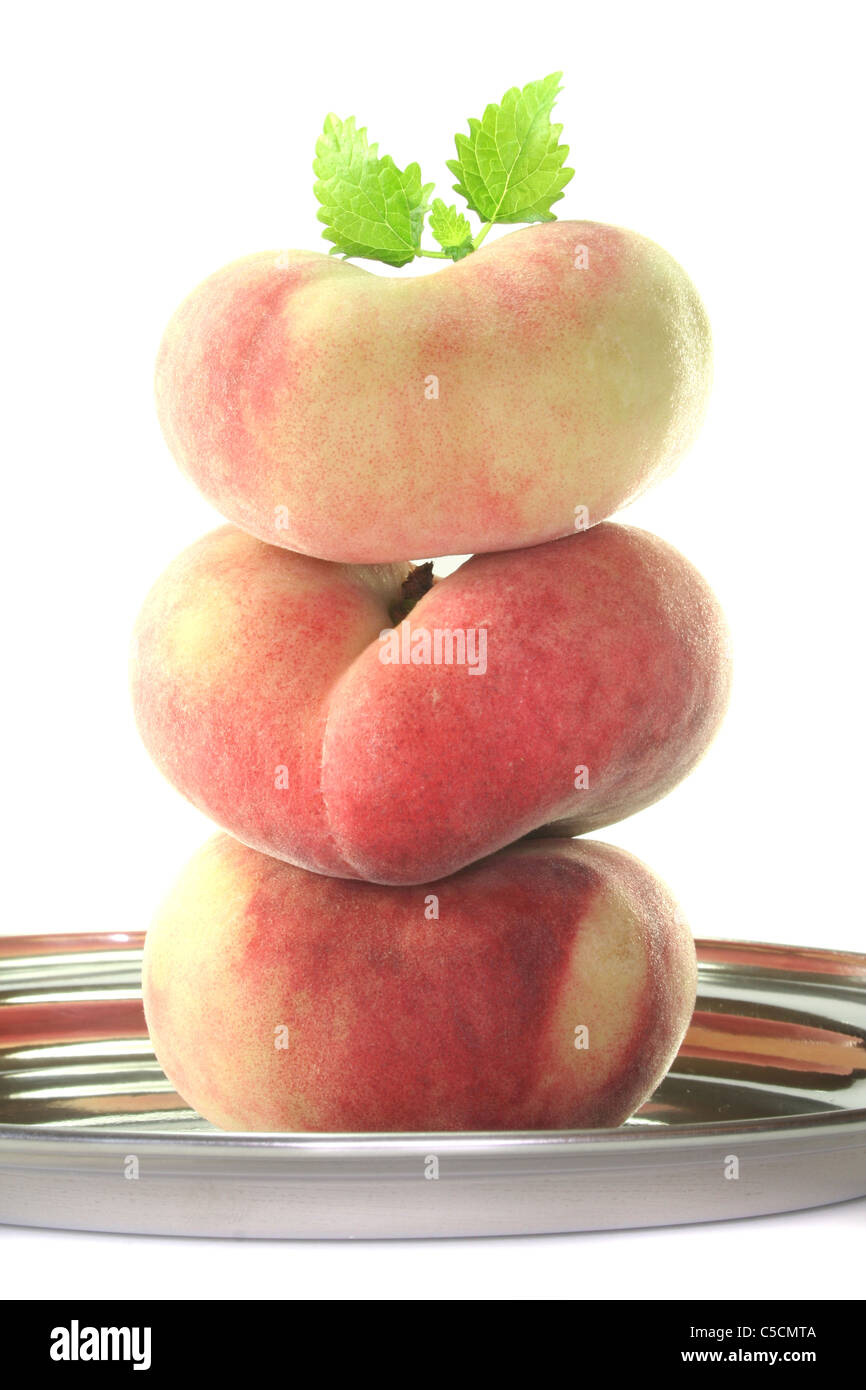 a stack of fresh mountain peaches with lemon balm on white background Stock Photo