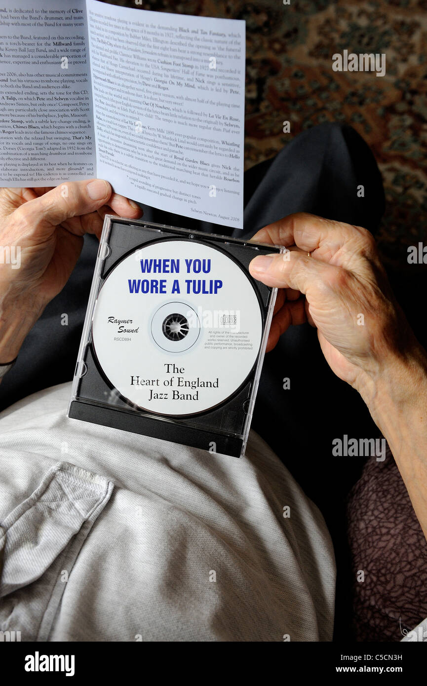 pensioner looking at jazz compact disc england uk Stock Photo