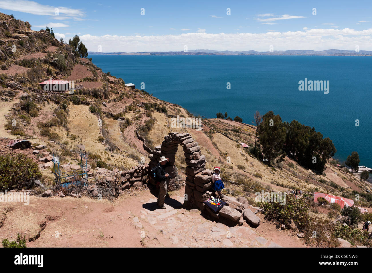 A young girl sits by a stone archway on the island of Taquile on Lake Titicaca Stock Photo