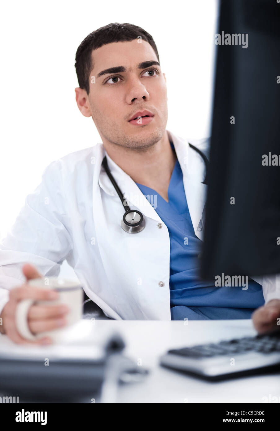 Young ethnic doctor looking deeply at the computer in his office Stock Photo