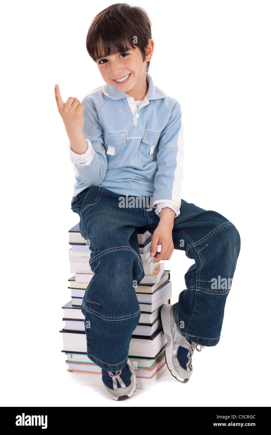 Young boy sitting over tower of books on white background Stock Photo