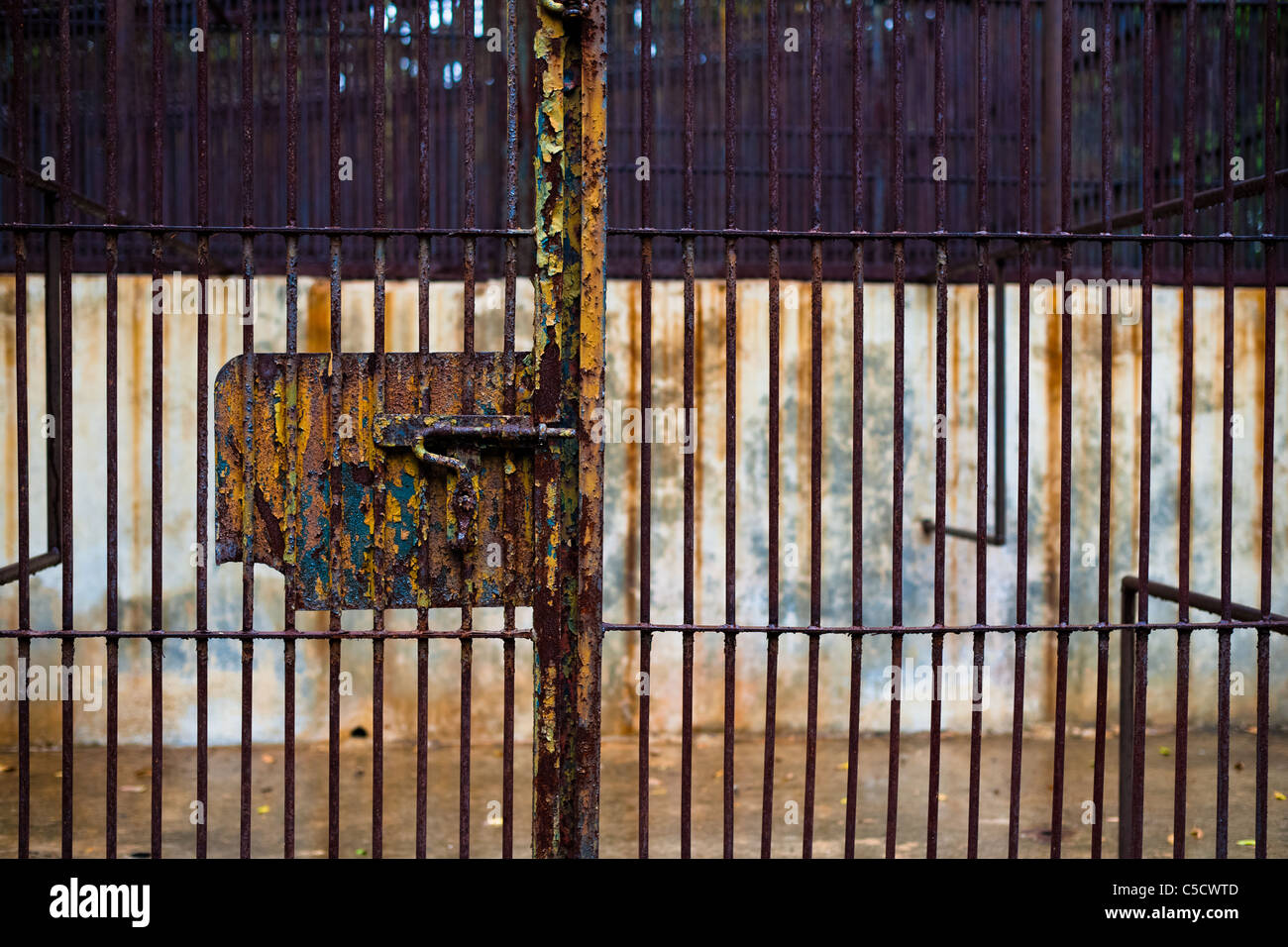 An empty concrete cage with rusted bars in the monkey area of the