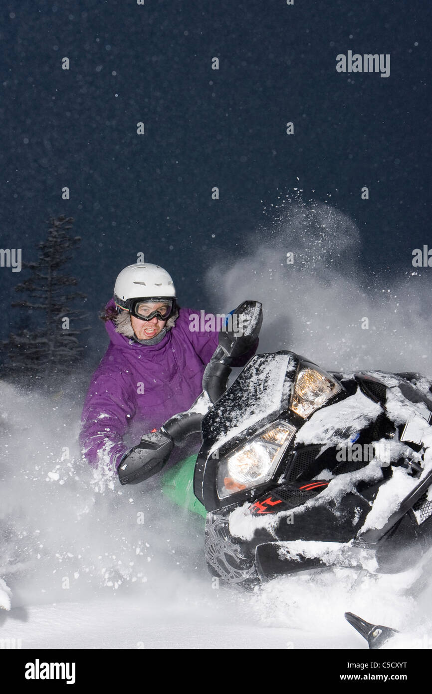 View of a snowmobiler in full speed against blue sky Stock Photo